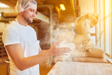 Mehl staubt beim Backen in Bäckerei von Händen des Bäckers