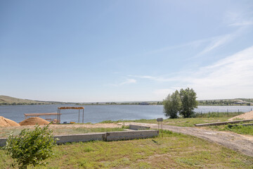 Fototapeta premium A small sandy beach on a pond with a pier and pleasure boats. Eastern Europe, summer, clear weather.