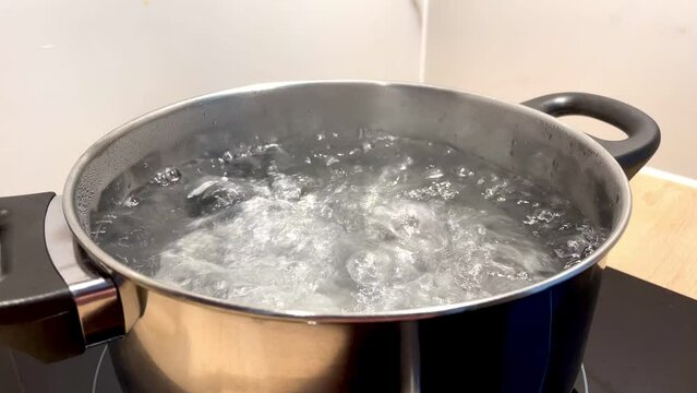 Water boiling, close-up in pot of boiling water. Bubbles on the water. 4K Footage