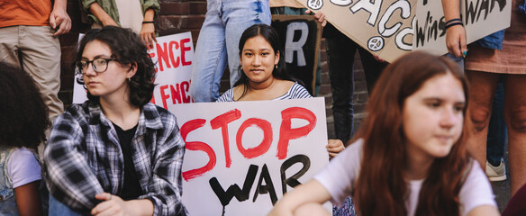 Young woman holding an anti-war banner during a protest - obrazy, fototapety, plakaty