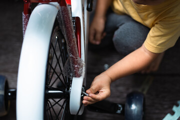 Obraz premium Close up kid hand is trying help father to assemble new bicycle by himself, concept of learning, practice and practical life skill for kid education and development at home in family life.