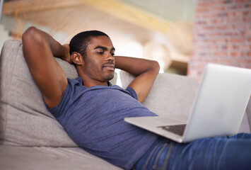 Relaxing with the whole world at my fingertips. Cropped shot of a handsome young man using his...