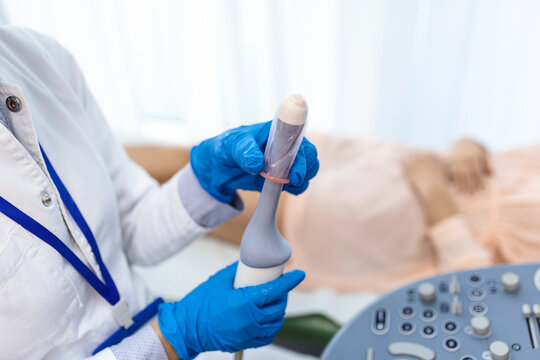 Gynecologist places ultrasound probe cover on a transvaginal ultrasound scanner for vaginal examination of a woman using an ultrasound machine. Ultrasound of the pelvic organs. Shooting close-up.