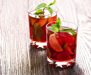 Refreshing summer alcoholic cocktail with strawberry, mint, lime on wooden background. Selective focus.