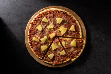 Hawaiian pizza with pineapple,ham and cheese on black stone