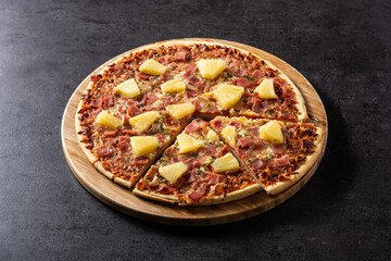 Hawaiian pizza with pineapple,ham and cheese on black stone