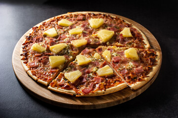 Hawaiian pizza with pineapple,ham and cheese on black stone