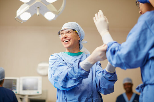Protecting themselves against germs. Shot of surgeons putting on surgical gloves in preparation for a surgery.