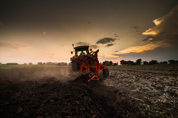 Fototapeta premium Tractor on the field during sunset.