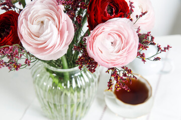 Bouquet of red and pink Persian buttercups on a white table. Scandinavian style. Place for text