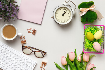 Desktop. Glasses coffee cup notepad on keyboard alarm clock on table with easter decorations.