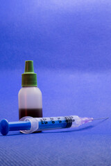A syringe and a medicine bottle with blue background