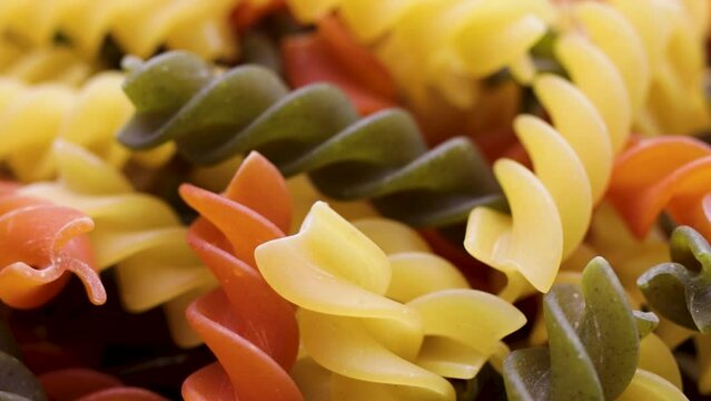 Three Colors Pasta made from durum wheat. Pasta fusilli tricolor background. Abstract texture of colorful pasta. pattern of macaroni. Bright multicolor food backdrop. Uncooked colored noodles.