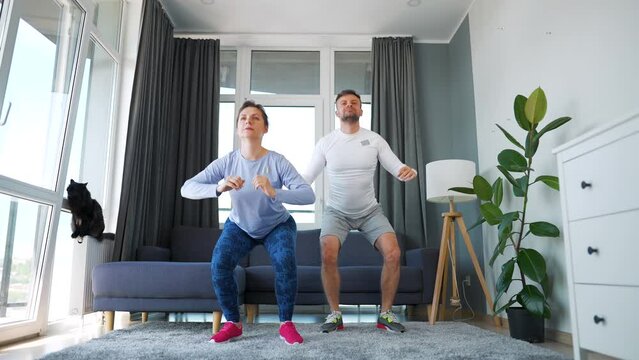 Caucasian couple is doing cardio exercise at home in cozy bright room, slow motion.