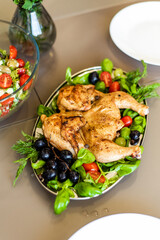 Finished tapaca chicken with a crispy crust lies in a plate on a bed of fresh vegetables. A homely atmosphere and a feast. Recipe for cooking chicken. Georgian national dish.