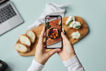 Top view of young woman taking aesthetic photo of food using smartphone in home studio, copy space - obrazy, fototapety, plakaty
