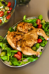Finished tapaca chicken with a crispy crust lies in a plate on a bed of fresh vegetables. A homely atmosphere and a feast. Recipe for cooking chicken. Georgian national dish.
