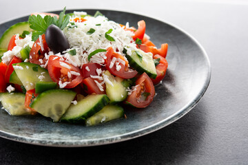 Traditional Bulgarian shopska salad with tomato,cucumber and bulgarian sirene cheese on black background	