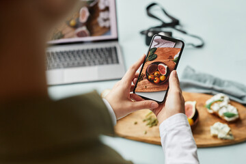 Close up of young woman taking aesthetic photo of food using smartphone for social media, copy space