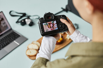 Close up of food photographer working in home studio, focus on digital camera with image on screen,...