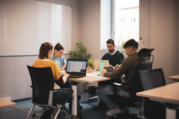 Diverse group of young business people discussing a work project while sitting together at a table in a modern office. coworking concept