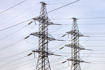 High voltage power lines pylons and electrical cables on a clear blue sky background. Modern infrastructure of high voltage transmission lines. Overhead power lines towers equipment. Energy industry.