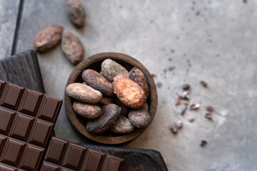Organic cocoa beans in a bowl on a black background with a chocolate bar. cooking background, top...