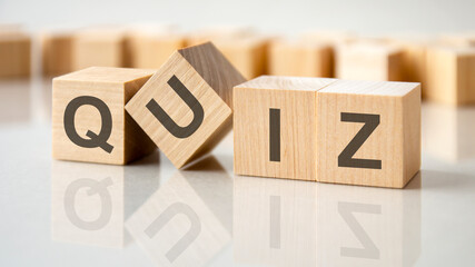 four wooden blocks with the letters quiz on the bright surface of a gray table, business conceptual word collected of of wooden elements with the letters