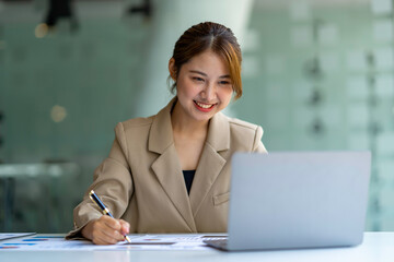 Beautiful Asian business woman working at the office with laptop.