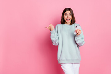 Photo of impressed bob hairstyle young lady hold telephone index promo wear hoodie isolated on pink...