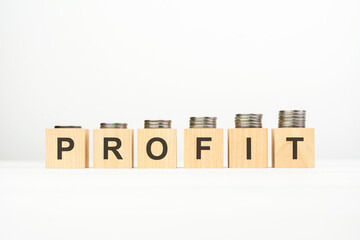 profit text written on wooden block with stacked coins on white background