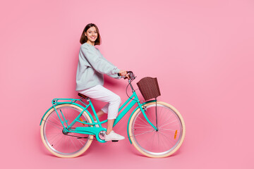 Full length profile side photo of youth cheerful girl enjoy trip on bicycle isolated over pink color background