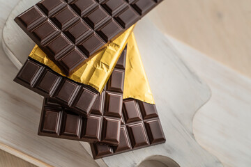 Chocolate bars with open gold cover. Stack of chocolate bars. Flat lay composition with delicious chocolate isolated on white background. Space for text