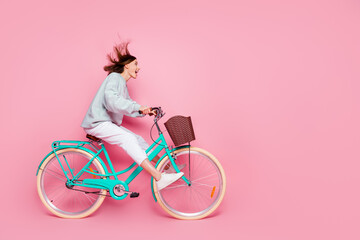 Full length profile side photo of young excited girl have fun look empty space riding bicycle...