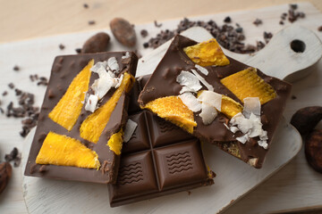 Raw Vegan Handmade Chocolate with dried mango fruits and coconuts slices close up. Chocolate bar with mango on a light background
