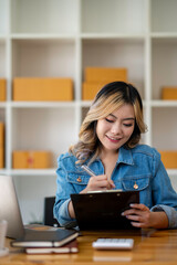 Starting Small business entrepreneur SME freelance,Portrait young woman working at home office, BOX,smartphone,laptop, online, marketing, packaging, delivery, SME, e-commerce concept.