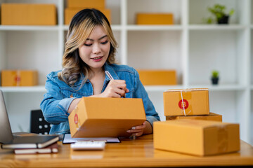 Starting Small business entrepreneur SME freelance,Portrait young woman working at home office, BOX,smartphone,laptop, online, marketing, packaging, delivery, SME, e-commerce concept.