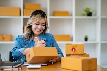 Starting Small business entrepreneur SME freelance,Portrait young woman working at home office, BOX,smartphone,laptop, online, marketing, packaging, delivery, SME, e-commerce concept.