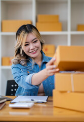 Fototapeta na wymiar Starting Small business entrepreneur SME freelance,Portrait young woman working at home office, BOX,smartphone,laptop, online, marketing, packaging, delivery, SME, e-commerce concept.