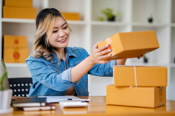 Starting Small business entrepreneur SME freelance,Portrait young woman working at home office, BOX,smartphone,laptop, online, marketing, packaging, delivery, SME, e-commerce concept.