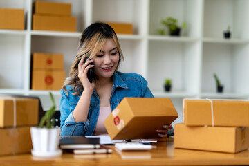 Fototapeta na wymiar Starting Small business entrepreneur SME freelance,Portrait young woman working at home office, BOX,smartphone,laptop, online, marketing, packaging, delivery, SME, e-commerce concept