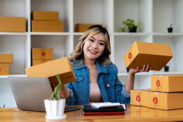 Fototapeta na wymiar Start up small business entrepreneur SME or freelance asian woman using laptop with box, Young success Asian woman with her hand lift up , online marketing packaging box and delivery, SME concept.