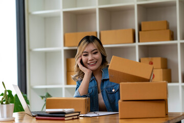 Start up small business entrepreneur SME or freelance asian woman using laptop with box, Young success Asian woman with her hand lift up , online marketing packaging box and delivery, SME concept.