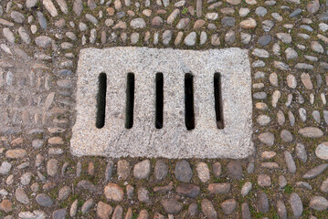 Ancient stone water drain in cobbled street, top view
