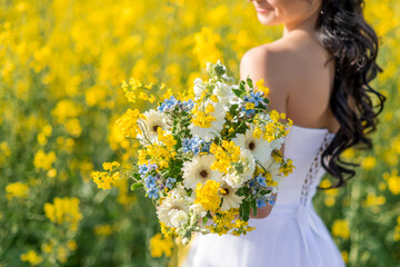 close-up of a wedding bouquet with yellow, white and blue flowers in the hands of the bride....