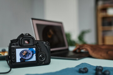 Close up of photo camera with food photography image on screen and laptop in background, copy space