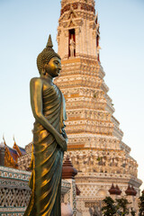 Buddha sculpture in front of a temple tower, Bangkok, Thailand