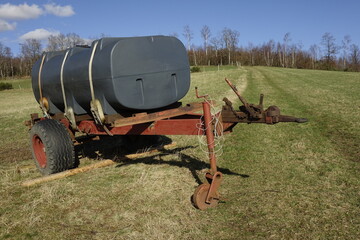 Black and red manure spreader hanger on a hilly meadow (horizontal), Ruckersfeld, NRW, Germany