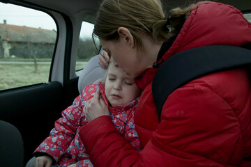 The refugees fleeing the war. Mother and her daughter in car. Refugees, war crisis concept.