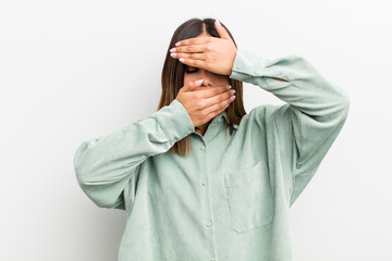 pretty hispanic woman covering face with both hands saying no to the camera! refusing pictures or...